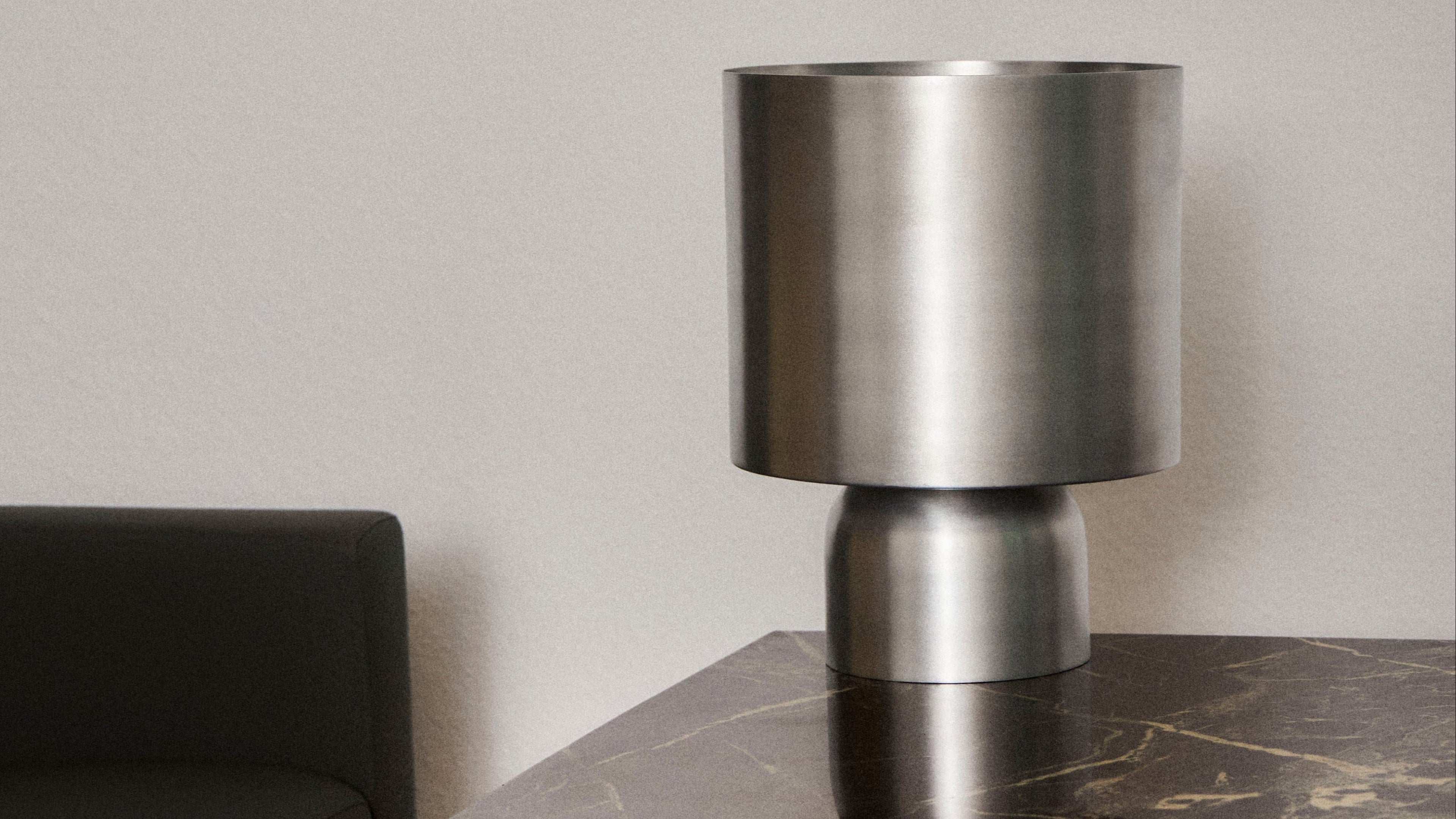 Metallic cylindrical lamp on a dark surface with a neutral background